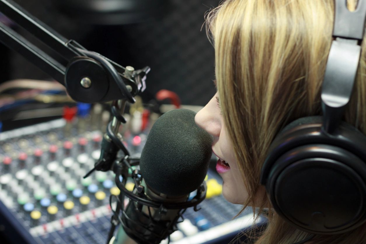 A woman with headphones on talking into a microphone.